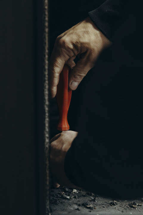 Close-up van een monteur die met een schroevendraaier werkt aan het onderhoud van een haard. Regelmatig professioneel onderhoud is essentieel voor de veiligheid en optimale prestaties van de haard.