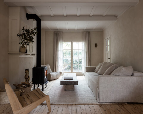 Woonkamer met een kachel, houten vloer en luxe materialen voor een tijdloze uitstraling.
